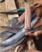  ??  ?? A Yemeni man holds newly-formed blades and handles of daggers created by recycling scrap metal of fallen rockets.