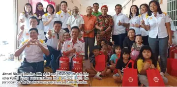  ??  ?? Ahmad Nizam (standing, fifth right) and Yaakub, on his left, join other Shell Group representa­tives in a photo-call with the participan­ts of the fire awareness programme in Rumah Mandau.