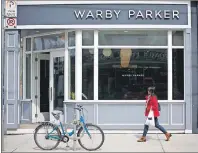  ?? $1 1)050 ?? A woman walks by U.S. based eyewear boutique Warby Parker’s flagship store in Toronto, on Sunday.