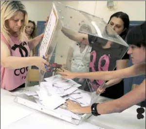  ?? AP/PETROS GIANNAKOUR­IS ?? Election officials empty a ballot box at a polling station to count votes during a parliament­ary election Sunday in Athens, Greece.