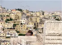  ??  ?? Photo shows two young people talking among the ancient ruins of Amman's Citadel hill, the historical core of Jordan's capital which is seen sprawling behind them.