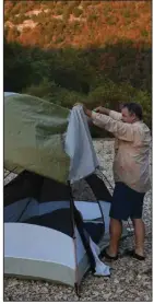  ?? (Arkansas Democrat-Gazette) ?? The author spreads a rainfly over his tent last Sunday on a Buffalo River gravel bar.