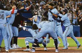  ?? Jon Blacker / Associated Press ?? Blue Jays second baseman Marcus Semien (second from front right) celebrates with teammates after hitting a three-run walkoff homer in the ninth inning of Toronto’s win over Oakland.