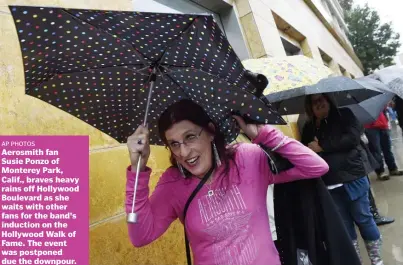  ?? AP PHOTOS ?? Aerosmith fan Susie Ponzo of Monterey Park, Calif., braves heavy rains off Hollywood Boulevard as she waits with other fans for the band's induction on the Hollywood Walk of Fame. The event was postponed due the downpour.