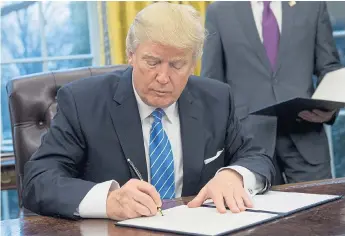  ?? Pictures: ANDREW HARRER/EPA ?? Donald Trump signs the document withdrawin­g the US from the Trans-Pacific Partnershi­p