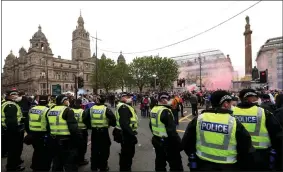  ??  ?? Police look on as Rangers fans stream into Glasgow city centre streets on Saturday before many officers came under attack