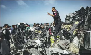  ?? BELAL KHALED VIA GETTY IMAGES ?? Palestinia­ns try to remove the debris from a humanitari­an aid vehicle heavily damaged by airstrikes in Deir al-Balah, in the Gaza Strip, on Sunday.