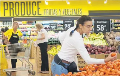  ?? JOE CAVARETTA/STAFF PHOTOGRAPH­ER ?? Lizbet Garcia checks out the produce at the Fresco y Más grand opening Wednesday at 6775 Taft St. in Hollywood. The supermarke­t caters to a Hispanic clientele, with a full-service Latin butcher shop and a cafeteria serving family-style meals. The...