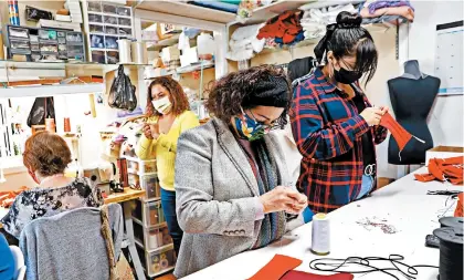  ?? GARY CORONADO/LOS ANGELES TIMES ?? Lilia Cerpas, center, and sister Vicky Cerpas, make masks April 3 at Genesis Bridal Boutique in Santa Ana, Calif.