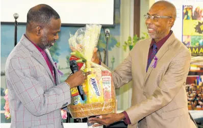  ?? CONTRIBUTE­D ?? Denzil Thorpe (left), permanent secretary in the Ministry of Culture, Gender, Entertainm­ent and Sport, presents a gift basket to the pastor of the Constant Spring Road Church of God, the Rev George Lewis, following the church service to recognise the Internatio­nal Day for the Eliminatio­n of Violence against Women on Sunday, November 21. The day will be observed on November 25.