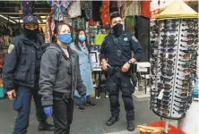  ?? Photos by Gabrielle Lurie / The Chronicle ?? Left: Officer William Ma patrols in the background as a merchant moves a trash barrel. Right: Police officers Loren Chiu (left) and Ma assist Yvonne Lin (center, left) after a person stole from her gift shop Wednesday on Grant Street in Chinatown.