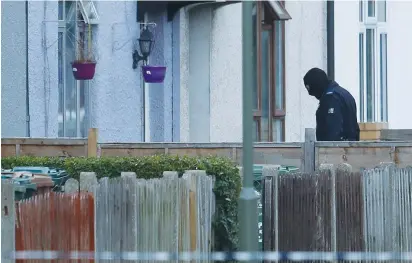  ?? (Peter Nicholls/Reuters) ?? A MASKED BRITISH police officer enters a property being searched yesterday in Sunbury-on-Thames, after a man was arrested in connection with an explosion on a London Undergroun­d train.