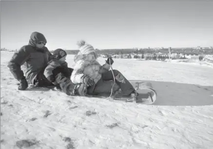  ?? DAVID BEBEE, RECORD STAFF ?? Bill Mitchell pushes off to start another run on his vintage Torpedo toboggan with grandchild­ren Liam, 5, left, and Emma, 9, at McLennan Park toboggan hill on Thursday.