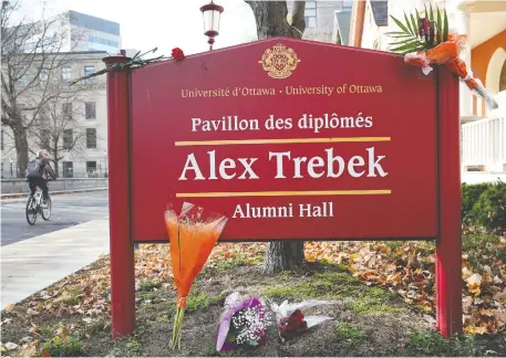  ?? TONY CALDWELL ?? Flowers are left by the Alex Trebek Hall sign at the University of Ottawa on Monday in memory of the beloved TV host.