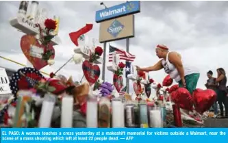  ?? EL PASO: A woman touches a cross yesterday at a makeshift memorial for victims outside a Walmart, near the scene of a mass shooting which left at least 22 people dead. — AFP ??