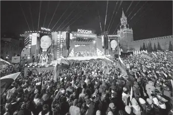  ?? Alexander Zemlianich­enko Associated Press ?? RUSSIAN President Vladimir Putin’s image is projected onto screens as he attends a concert in Moscow’s Red Square. Monday’s event marked his electoral win as well as the 10th anniversar­y of Crimea’s annexation.