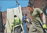  ?? HECTOR RETAMAL / AGENCE FRANCE-PRESSE ?? Workers install a water tank on a building on Lexington Ave on May 9 in New York.