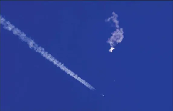  ?? CHAD FISH VIA AP ?? The remnants of a large balloon drift above the Atlantic Ocean, just off the coast of South Carolina, with a fighter jet and its contrail seen below it, is pictured in this Feb. 4 photograph. The downing of the suspected Chinese spy balloon by a missile from an F-22 fighter jet created a spectacle over one of the state’s tourism hubs and drew crowds reacting with a mixture of bewildered gazing, distress and cheering.