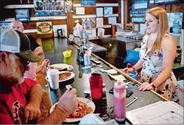  ?? KEITH SRAKOCIC/AP PHOTO ?? Kendra Snyder, right, talks with patrons Monday at Checkers Bar &amp; Grill in Mount Union, Pa. At age 12, Snyder passed out from a condition where her heart was missing over 1,000 beats every day. She had heart surgery when she turned 20, and doctors said the problem seemed to be fixed. Her cardiologi­st wanted to know whether her condition was inherited or not, so genetic tests were done. In March, Kendra was told her testing was inconclusi­ve.