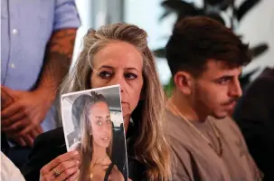  ?? (Ronen Zvulun/Reuters) ?? THE MOTHER of Mia Schem holds up a picture of her daughter who was kidnapped from Israel into the Gaza Strip, in Tel Aviv yesterday.