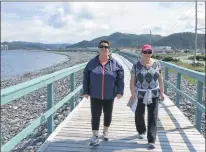  ?? ASHLEY FITZPATRIC­K/THE TELEGRAM ?? Donna Lambe (left) and Gail Ryan like to walk the boardwalk on the Placentia waterfront on a fine day. Both women recall past flooding in the community before protection­s such as the boardwalk and breakwater, and say sea level rise is not currently...