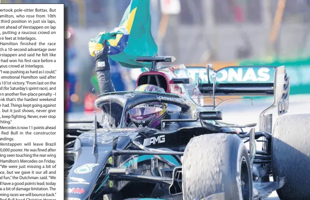  ?? AP ?? Mercedes’ Lewis Hamilton holds a Brazilian flag as he celebrates wining the Brazilian Formula One Grand Prix at the Interlagos racetrack in Sao Paulo, Brazil, yesterday.