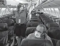  ?? Charlie Riedel / Associated Press ?? A Southwest Airlines flight attendant prepares a plane for takeoff. CEOS at Southwest and American say cabin filters are so efficient that face masks aren’t needed.