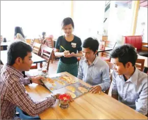  ?? VIREAK MAI ?? A waitress serves customers at the Pizza Company’s Riverside branch in 2014 .