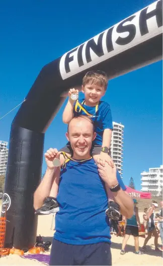  ??  ?? Louie Mathieson, 5, shows off his medal with dad Gavin after the Kokoda Beach Classic.