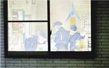  ?? — AFP photos ?? Police inspect the office where a policeman was shot dead in western Japan’s Hikone, Shiga prefecture.