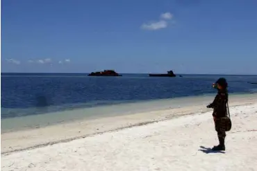  ?? AFP ?? ONGUARD A member of the Philippine military stands on the beach at Thitu (Pag-Asa) Island, which hosts a small town as well as an airstrip used for Filipino civilians and military flights in the disputed Spratly Islands in the South China Sea.