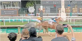  ?? GARY GRAVES THE ASSOCIATED PRESS ?? Spectators look on as horses approach the finish of a race at Churchill Downs in Louisville, Ky., on Saturday. The Kentucky Derby is expected to go off with full capacity at Churchill Downs this weekend.