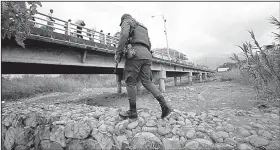  ?? AP/FERNANDO VERGARA ?? A police officer in La Parada, Colombia, patrols Tuesday near a bridge that connects Colombia and Venezuela.