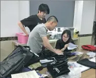  ??  ?? Hong Yihan, from Jinjiang Fengxing Garment Co, chats with colleagues about a new technology used in pants.
