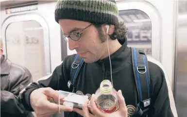  ?? OZIER MUHAMMAD/THE NEW YORK TIMES 2005 ?? A commuter on a New York City subway train listens to an ipod. Apple’s first-generation ipod, released in late 2001, could hold up to 1,000 songs. The company said production of the iconic music player ended this week after 21 years.