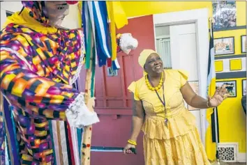  ?? Photograph­s by Nick Agro For De Los ?? CYNTHIA LEWIS talks about a Wanaragua warrior dance costume in the Garifuna Musuem of Los Angeles. The museum operates out of a house in South L.A., and aims to educate others on the history of the people.