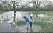  ??  ?? Children play at Primrose Hill Park turns a park walkway into a pond. (AP/Sheila Norman-Culp) in London as floodwater