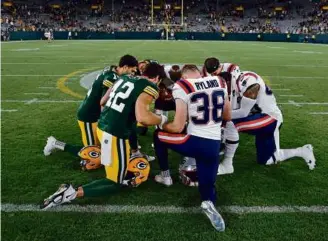  ?? JEFFREY PHELPS/ASSOCIATED PRESS ?? Finishing the game wasn’t a concern as Packers and Patriots players gathered in prayer after cornerback Isaiah Bolden suffered a head injury.