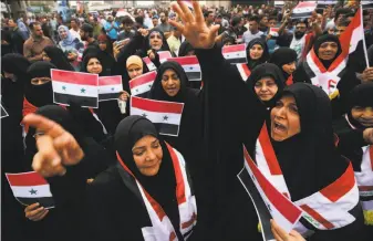  ?? Ahmad al-Rubaye / AFP / Getty Images ?? Iraqis wave Syrian flags during a protest in Baghdad against the U.S.-led air strikes on Syria. The U.S., Britain and France hit sites they said were linked to a chemical weapons program.