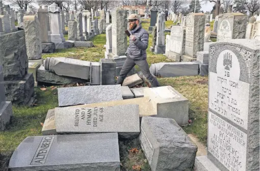  ?? JACQUELINE LARMA, AP ?? Rabbi Joshua Bolton of the University of Pennsylvan­ia surveys damaged headstones atMount Carmel Cemetery onMonday in Philadelph­ia. More than 100 headstones were vandalized at the Jewish cemetery.