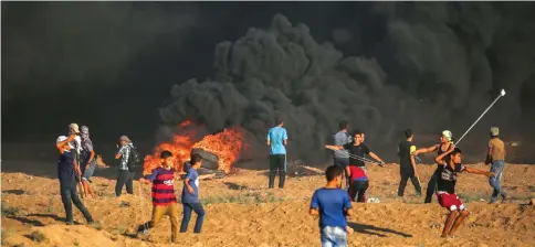  ??  ?? Palestinia­n youths using slingshots to hurl objects towards Israeli forces amidst clashes along the Israeli fence east of Gaza City as shown in this file photo. — AFP photo