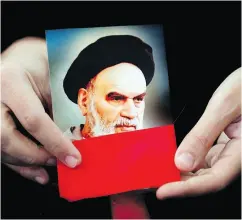  ?? HUSSEIN MALLA / THE ASSOCIATED PRESS ?? A Hezbollah supporter holds a portrait the late Iran revolution­ary founder Ayatollah Khomeini, whose influence is still being felt 40 years later in other countries .