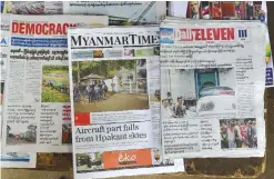  ??  ?? YANGON: A Myanmar Daily Eleven newspaper (right) displayed on a news stand in Yangon yesterday shows a front page picture of Than Htut Aung, CEO of the Eleven Media Group, raising his handcuffed hands while being put in a police vehicle at a police...