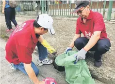  ??  ?? Two parishione­rs help one another in the cleaning campaign.