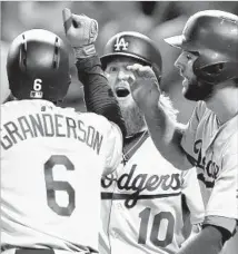  ?? Keith Srakocic Associated Press ?? DODGERS NEWCOMER CURTIS GRANDERSON is greeted by teammates Justin Turner, center, and Chris Taylor after hitting a seventh-inning grand slam against Gerrit Cole.