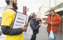  ?? Jessica Christian / The Chronicle ?? Carlo Mastrogiac­omo of San Francisco signs a petition to recall Gov. Gavin Newsom while at a market in San Francisco.