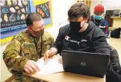  ?? CEDAR ATTANASIO AP ?? New Mexico Army National Guard specialist Michael Stockwell helps a student with a geology assignment.