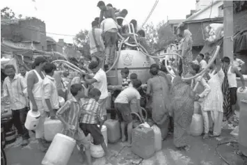  ?? ASSOCIATED PRESS ?? Residents crowd around a government tanker delivering drinking water at a slum in New Delhi, India.