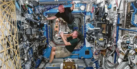  ?? NASA ?? Astronauts Terry Virts, bottom, and Scott Kelly perform eye exams while aboard the space station as part of ongoing studies on vision health in microgravi­ty.