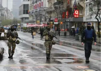  ?? YOUSSEF BOUDLAL/REUTERS ?? Belgian soldiers and police patrol central Brussels on Saturday. Belgium raised the city’s alert status to the highest level, closing the metro system and advising people to avoid crowded places.